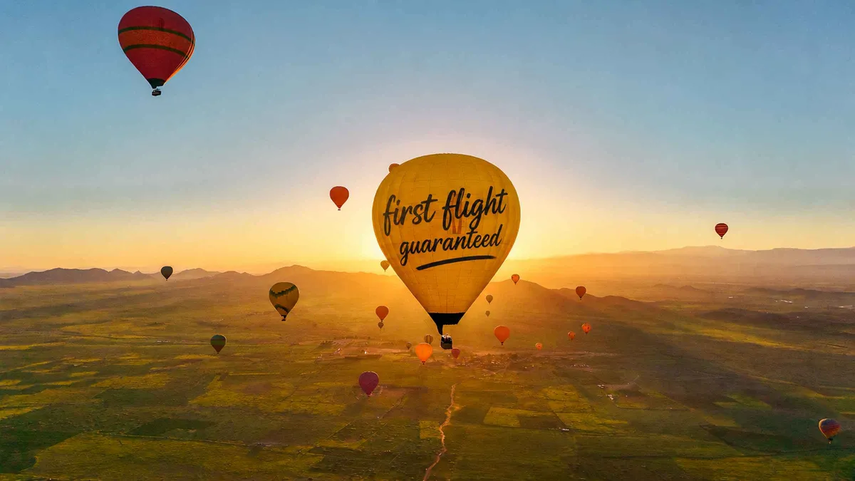 A hot air balloon basket with passengers watching sunrise over the Atlas Mountains on a hot air balloon ride in Marrakech, Morocco